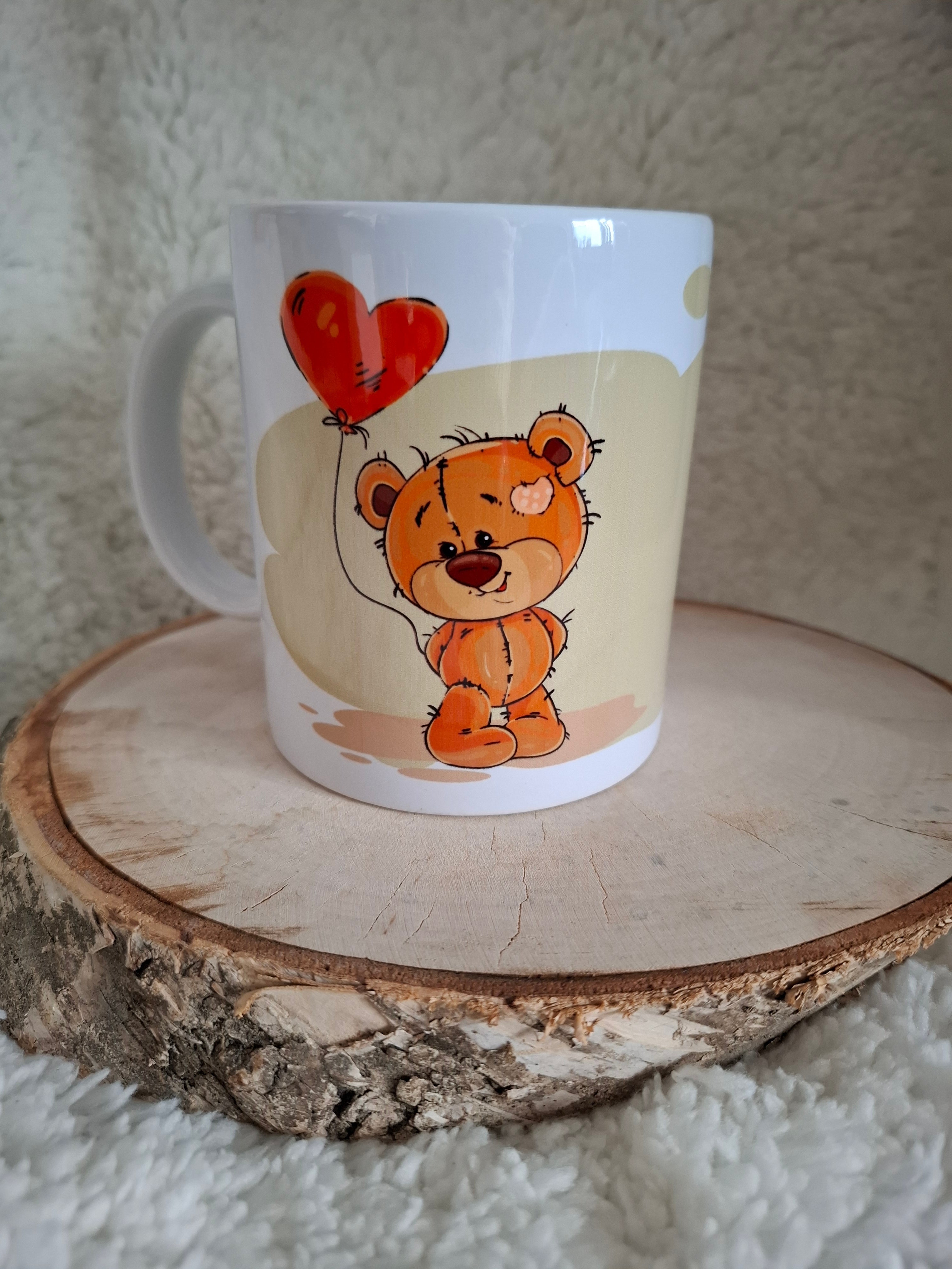 Becher mit einem süßen Bären, der einen Herzballon trägt, und dem liebevollen Spruch "Hab Dich Lieb".