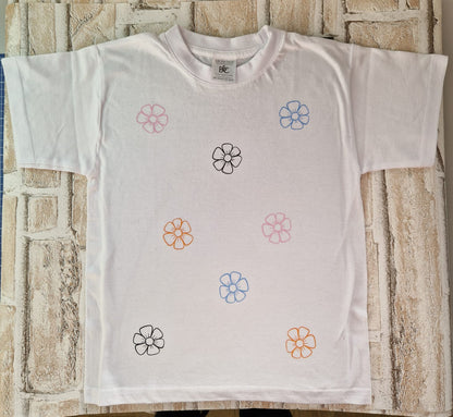 Bunt bedrucktes weißes T-Shirt mit floralen Designs, perfekt für einen frischen, kreativen Look.